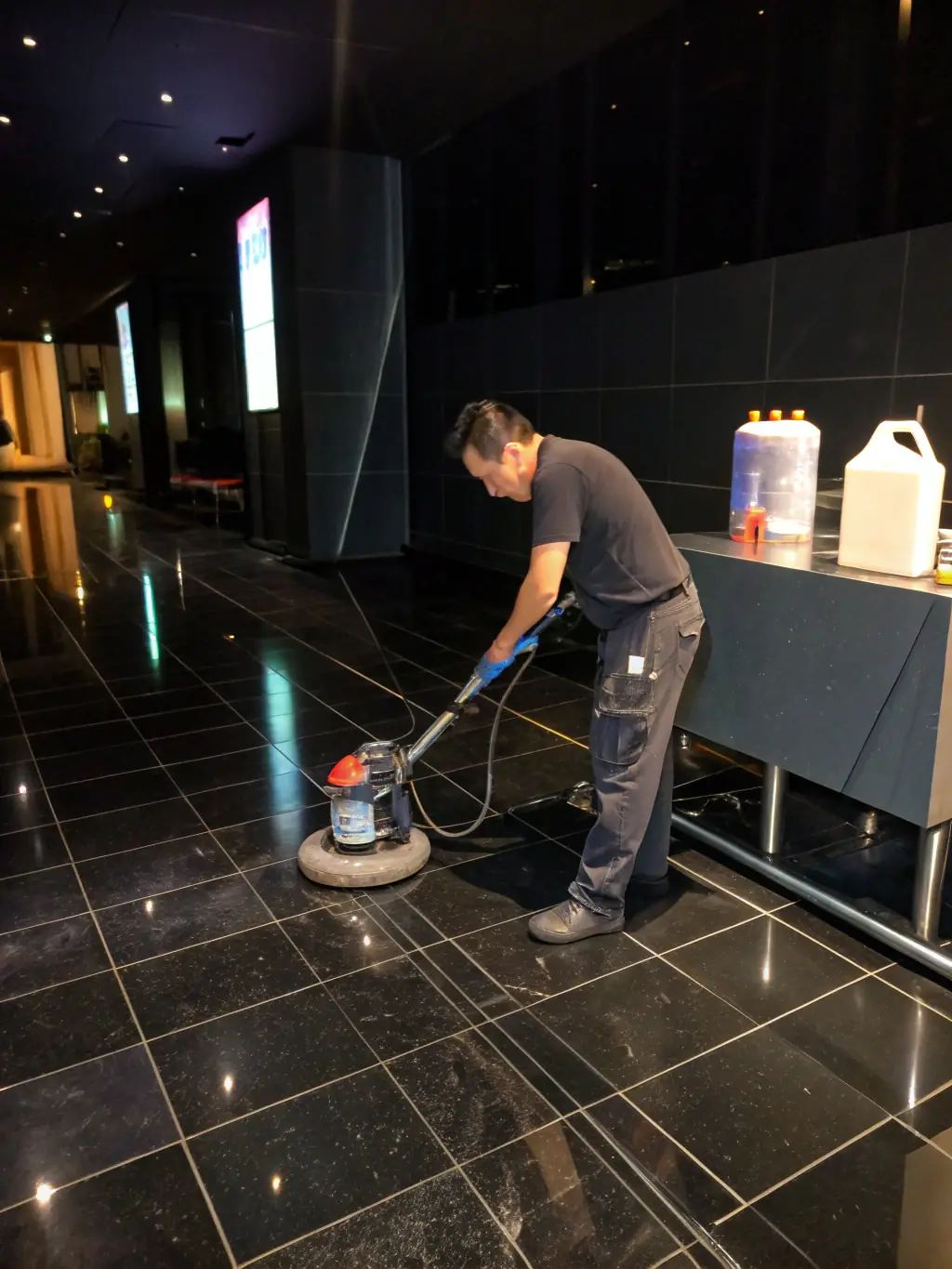 A Xiomara Commercial Cleaning employee using specialized floor cleaning equipment in a large commercial space, demonstrating advanced cleaning technology.
